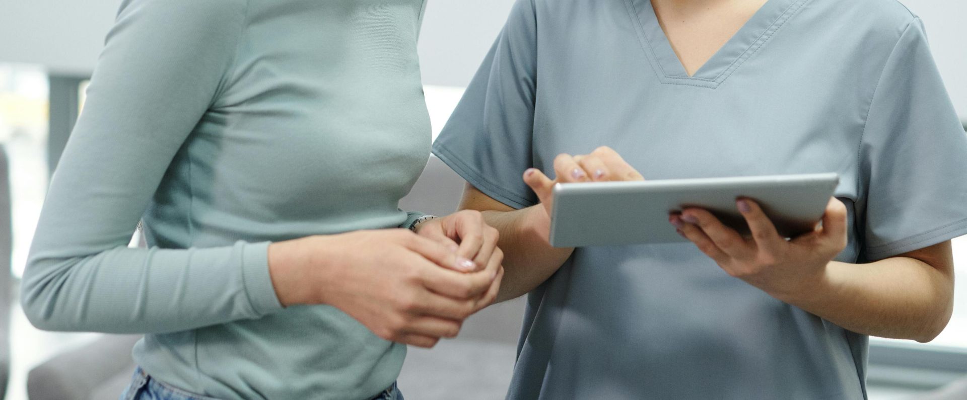 Healthcare professional using a tablet during a consultation inside a clinic.